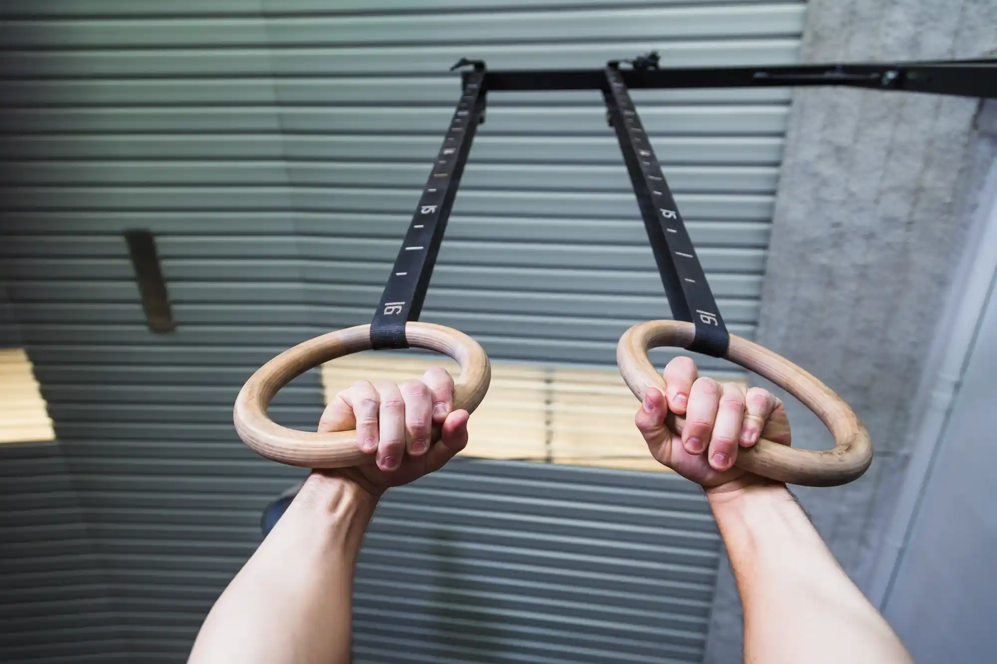 First-person view of a person hanging from gymnastic rings, demonstrating support grip strength