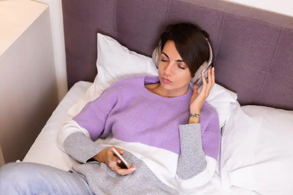 Woman listening to headphones in bed