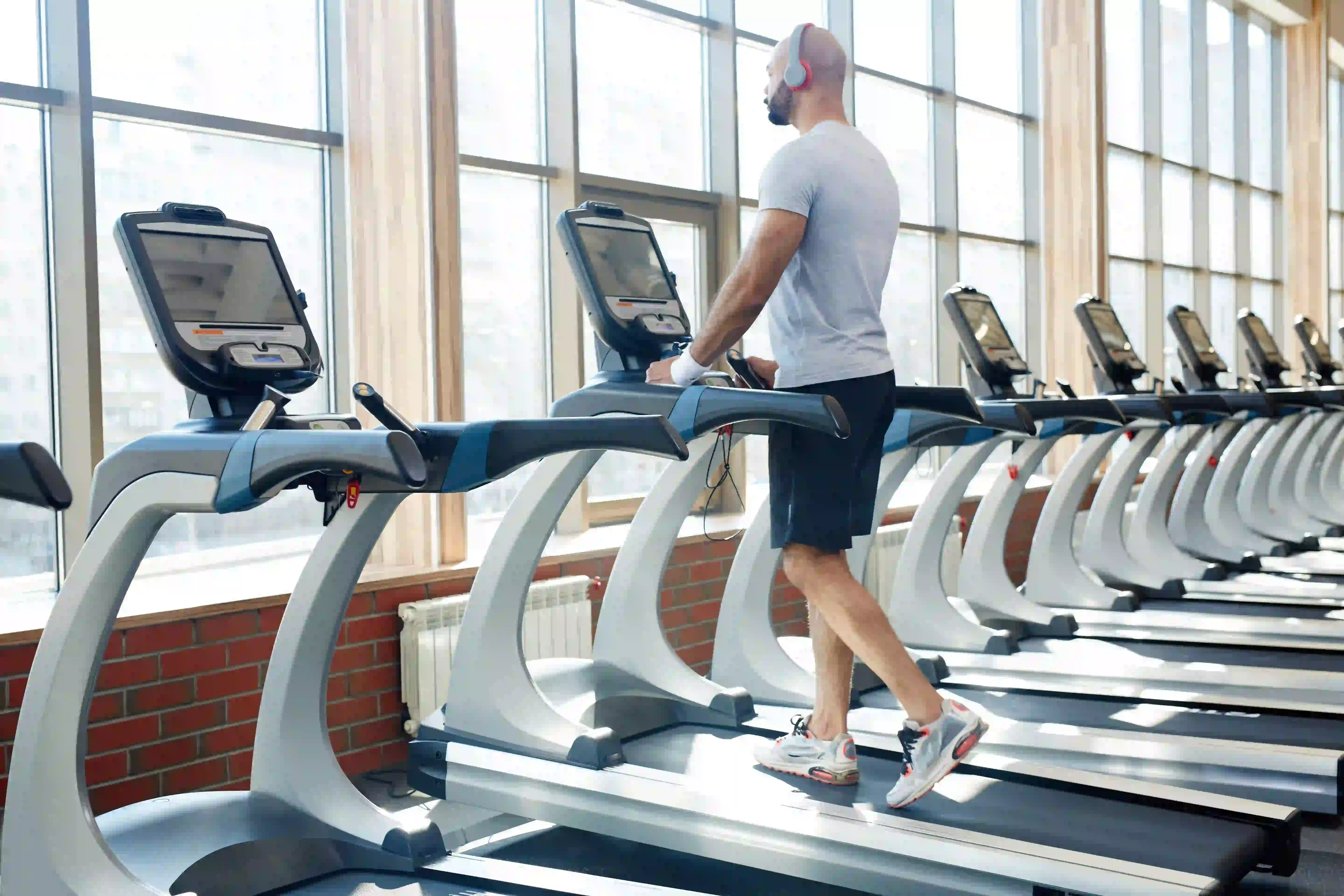 A man exercising on a treadmill in a gym with headphones